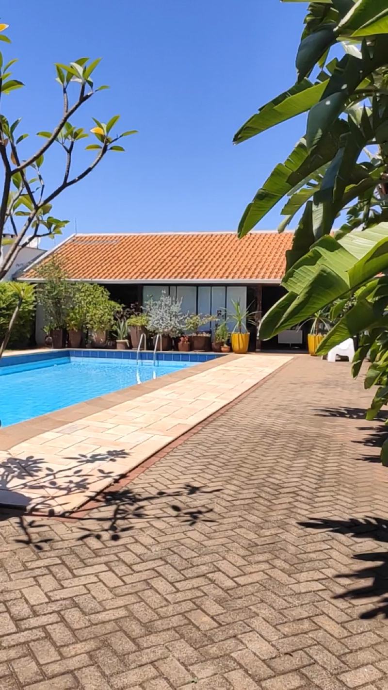 A casa e a piscina vistas do jardim, no sol da manhã
